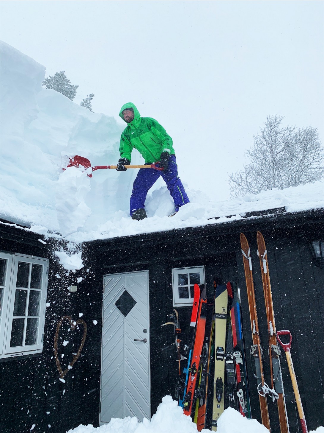 Sigbjørn Justnæs er i gang med å fjerne snø fra taket, han passer på at rømningsveien ikke blir blokkert.
